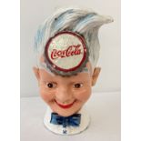 A painted cast iron money bank in the from of the Coca Cola sprite.