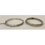 2 vintage silver hinged bangles with safety chains and half floral decoration.