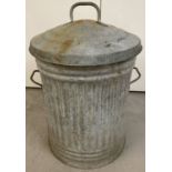 A vintage galvanised dustbin with lid and side carry handles.