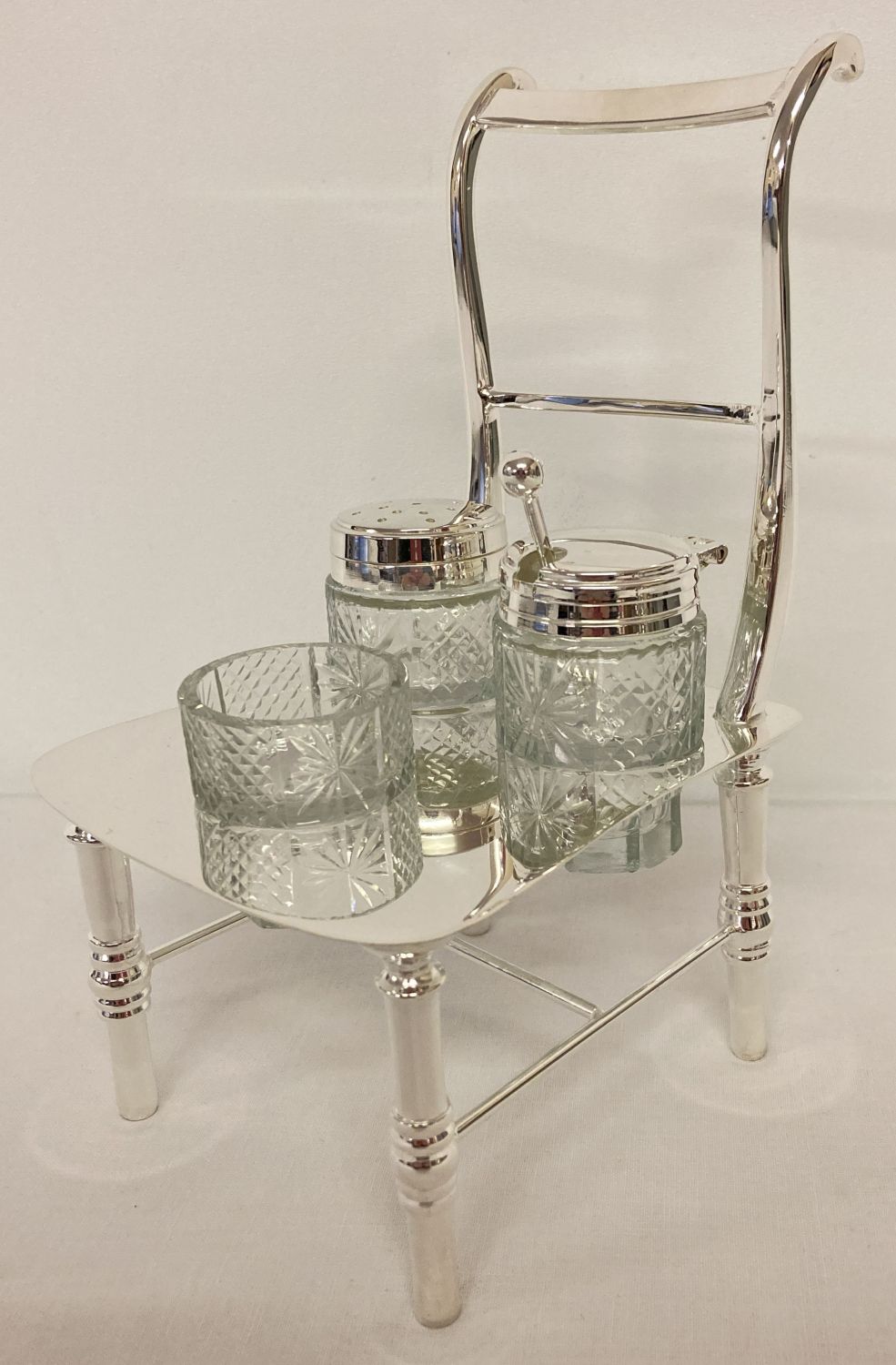 A silver plated and cut glass novelty cruet in the shape of a chair.