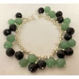 A white metal bracelet with faceted green and black glass beads and lobster clasp.
