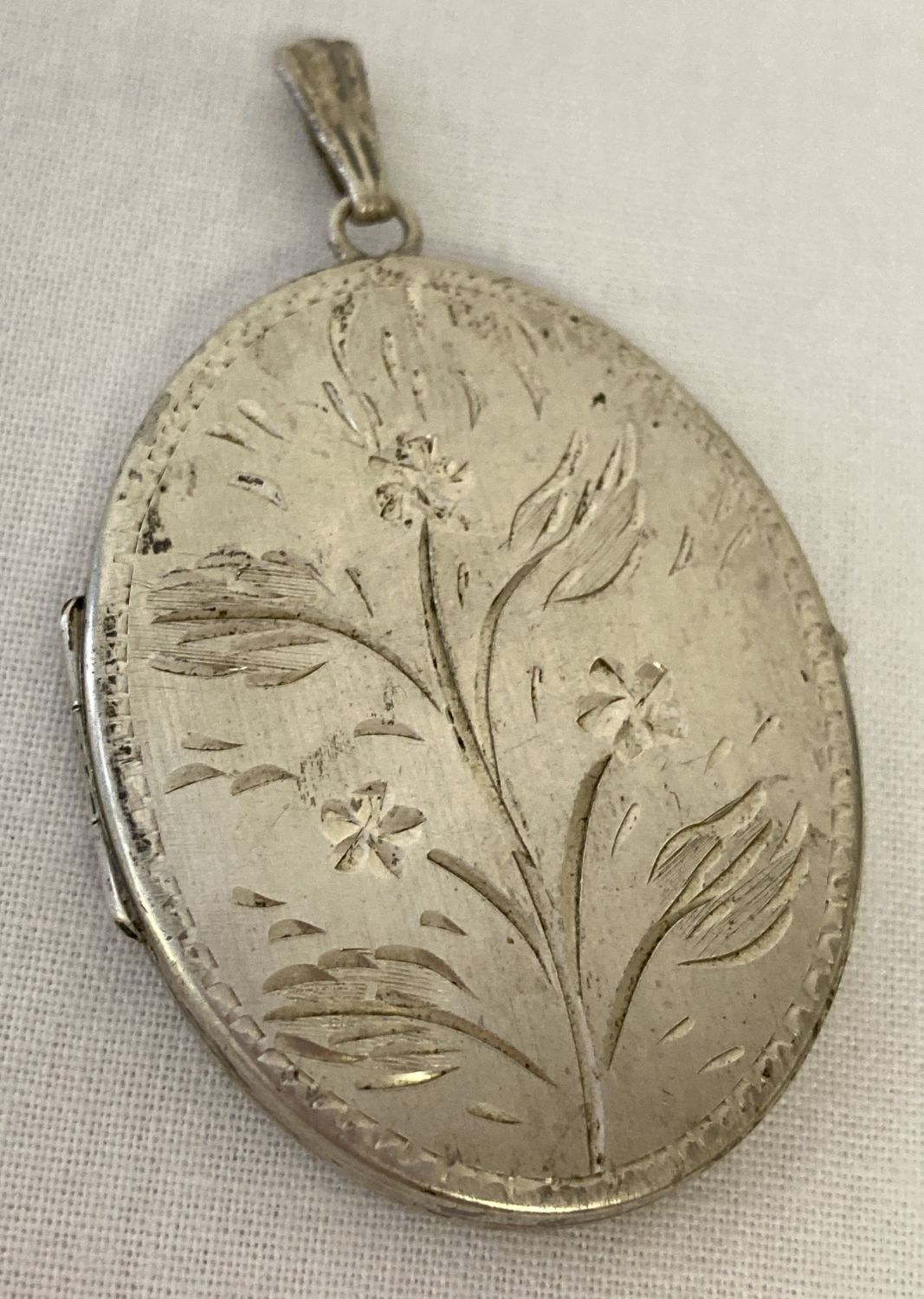 A large vintage silver oval locket with engraved flower decoration to front. Hallmarked to back.