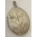 A large vintage silver oval locket with engraved flower decoration to front. Hallmarked to back.