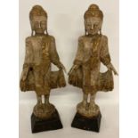 A pair of carved wooden buddha figures with gilt finish.