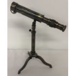 A small brass telescope mounted on an extending tripod base with folding feet.