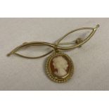 A 9ct gold bow design brooch with cameo drop. Cameo set in gold mount with rope design edges.