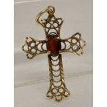 A gold filigree style cross shaped pendant set with an oval cut garnet. Tests as 9ct gold.