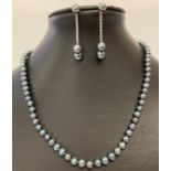 A peacock pearl necklace with silver clasp and matching 2-in-1 earrings.