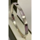 A modern design silver hinged bangle set with pale pink and white shell.