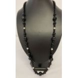 A 30" onyx bead necklace with fresh water pearls and white metal T bar clasp.