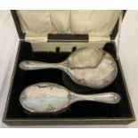 A cased Edwardian silver backed hairbrush and matching hand mirror.
