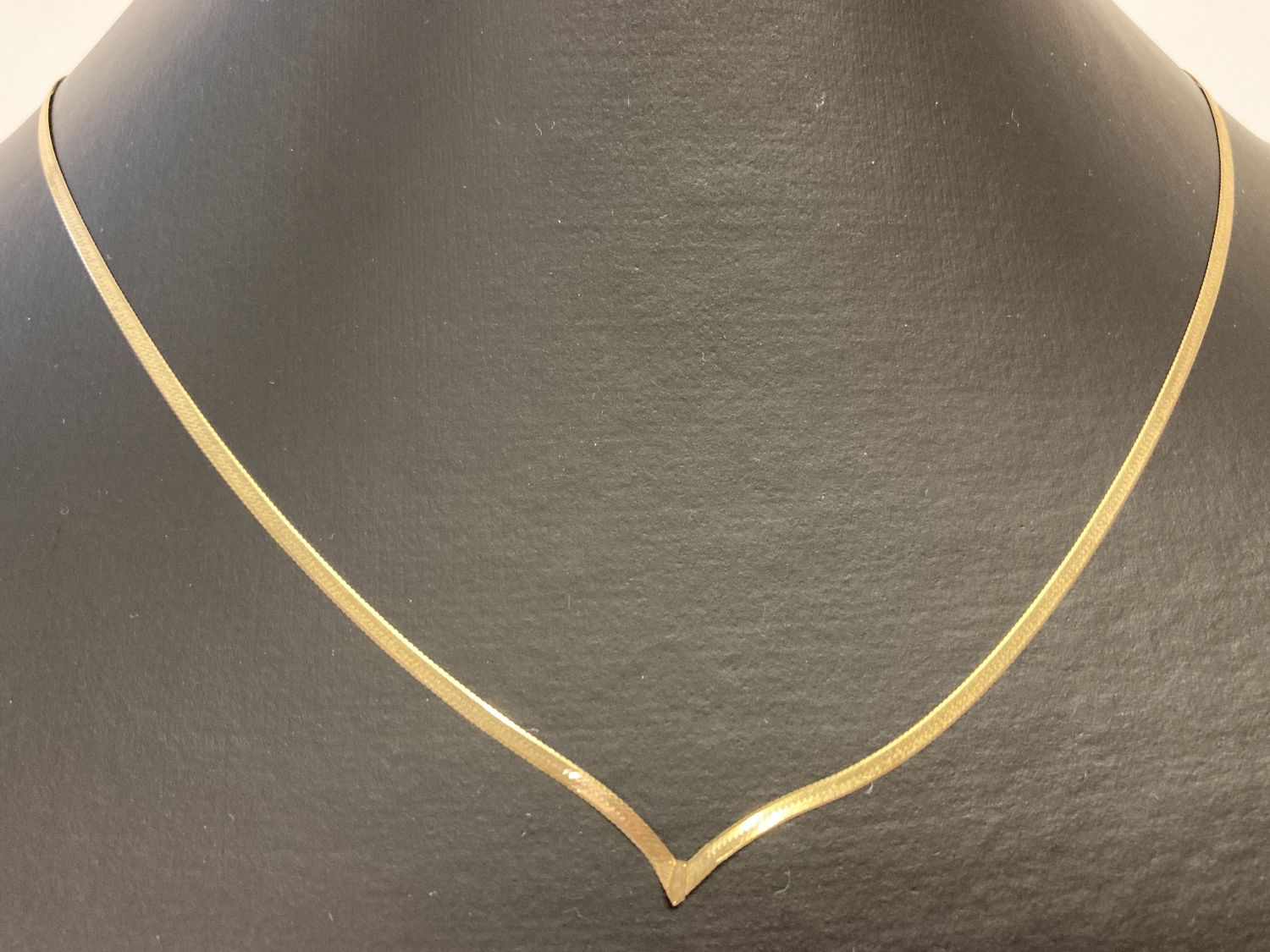 A 9ct gold flat herringbone style wishbone necklace.