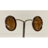 A pair of silver and amber stud style earrings with Art Nouveau style decoration.