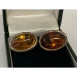 A boxed pair of silver cufflinks set with oval amber cabochons.