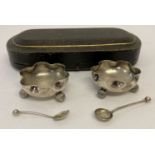 A pair of antique 3 footed silver salts with scalloped edge detail, in original case.