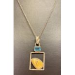 A silver necklace with square shaped pendant set with a Swiss blue topaz and a natural brown agate.