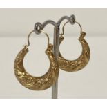 A pair of decorative gold hoop earrings. Twist design with floral detail. Tests as 9ct gold.