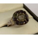 A Georgian gold mourning ring with central glass panel surrounded by round cut garnets, 1 missing.
