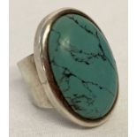 A large modern design silver dress ring set with an oval cut turquoise stone.