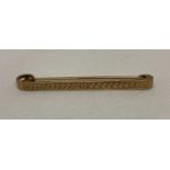 A 9ct gold tie pin with engine turned decoration to front. Marked 9ct to back with inscription.