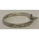 A Charles Horner silver hinged baby's bangle with half floral engraving and safety chain.