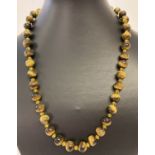 A 20" Tigers eye beaded necklace with yellow glass spacer beads and T bar clasp.