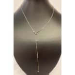 A silver long adjustable snake chain necklace with ball detail to clasp and end of chain.