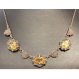 A vintage Art Deco style white metal necklace set with citrine and marcasite stones.