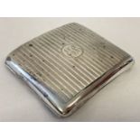 A silver cigarette case with engine turned decoration and engraved initials ER.