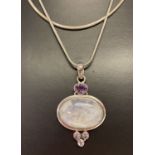 A modern design silver pendant set with a large moonstone and 4 amethysts on a 30 inch snake chain.