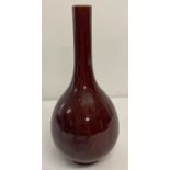 A red glazed Chinese slim necked vase of bulbous form.