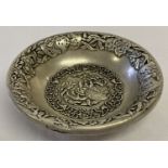 A decorative Chinese white metal dish with peach and blossom design to inner bowl.