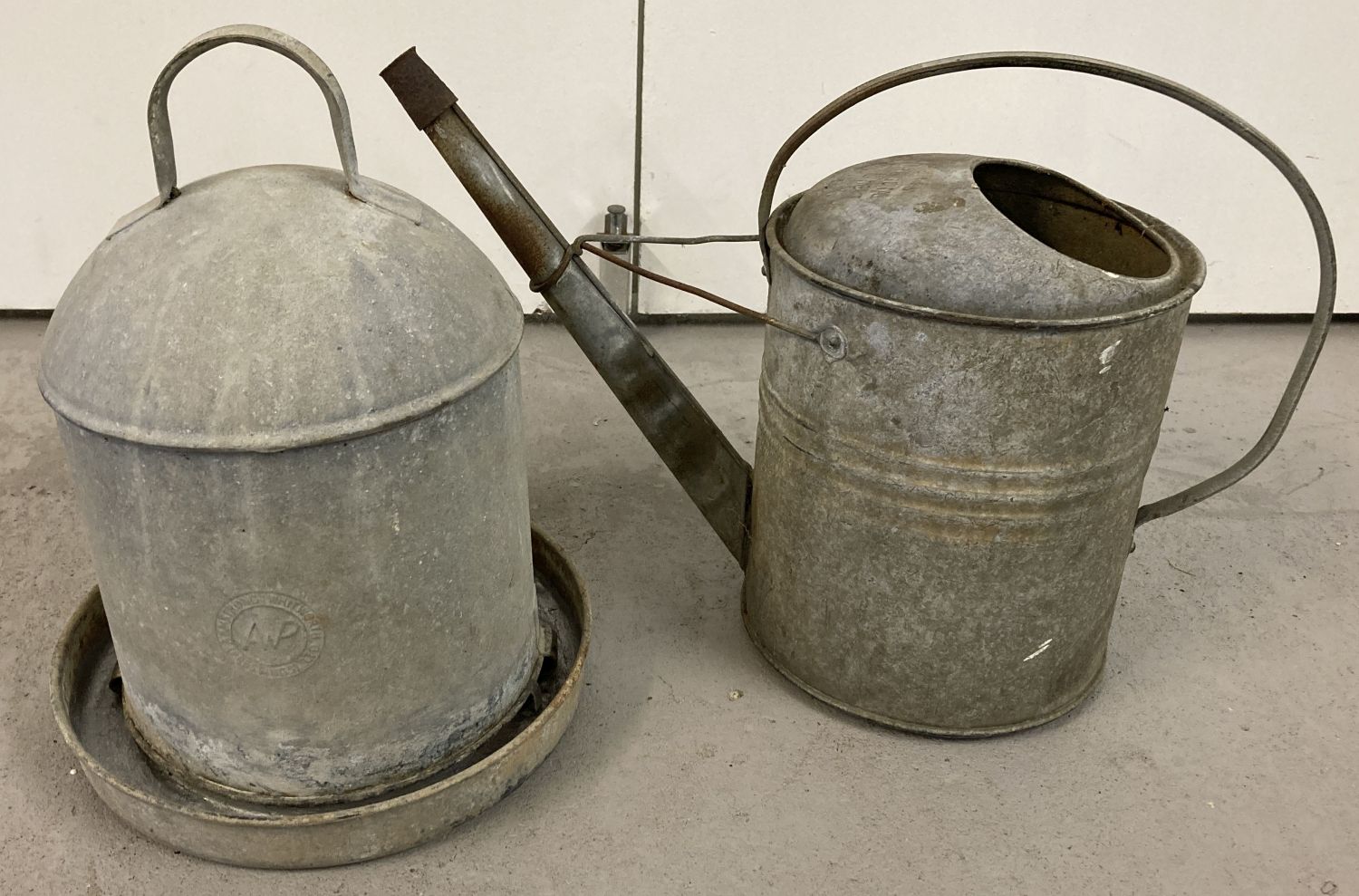 A vintage galvanised metal watering can together with a galvanised metal dome topped drinker.