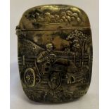 A brass vesta case featuring a man driving a car. Detailing to both sides.