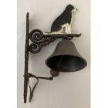 A painted cast metal wall hanging garden bell with collie dog detail.