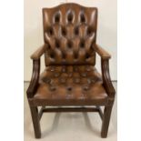 A modern dark wood framed brown leather button backed and seated arm chair.
