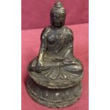 A small circular based hollow bronze figure of seated Buddha.