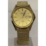 A vintage Seiko Quartz wrist watch. Gold face and case with luminous hands and day/date function.