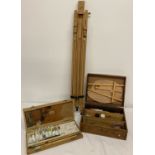 2 wooden boxes of artists paints, brushes and accessories together with a wooden tripod easel.