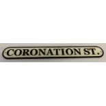 A cast iron wall hanging Coronation St. street sign, painted black and white.