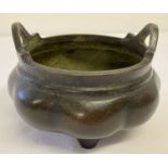 A large Chinese bronze censer with bulbous bowl, tripod feet and loop handles.