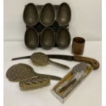 A box of assorted vintage metal ware items to include chocolate egg mould and wooden handled saw.
