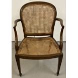 A curved cane back and seat armchair with column style legs and spade feet.