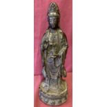 A hollow bronze figurine of Guan Yin standing atop a lotus flower.