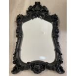 A large ornate wall hanging mirror with decorative black gloss frame.