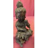 A Chinese hollow bronze shelf sitting figurine of a girl in seated position holding a flower.