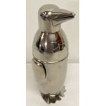 A silver plated cocktail shaker in the shape of a penguin.