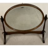An Edwardian oak framed, table top oval swing mirror with turned supports.