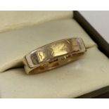 An 18ct gold wedding band with worn floral decoration.