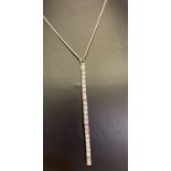 A modern design long drop silver pendant necklace set with cubic zirconia stones.